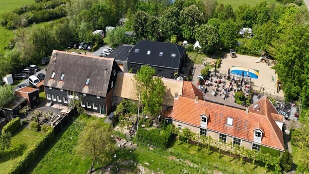 An aerial view of a rural property with multiple buildings, including a large house with a red-tiled roof, a smaller house with a dark roof, and a swimming pool area. - Stay at Oranjezon Dunes (Vrouwenpolder)