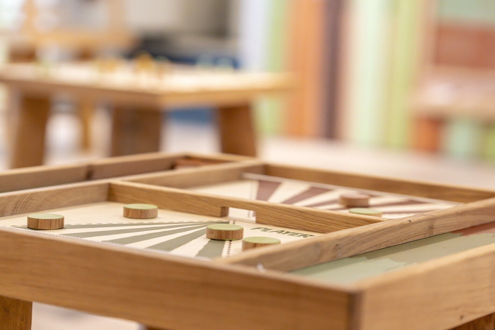 Un juego de mesa de madera con piezas y una etiqueta que dice 'PLAY', colocado sobre una mesa.