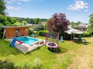 A backyard with a swimming pool, a slide, a trampoline, and outdoor furniture. - Ruhige Gartenwohnung in Dresden (Dresden)