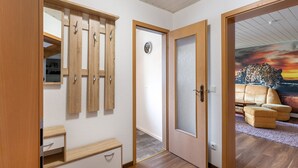 Una habitación con un armario de madera, una puerta con un reloj y un mural de leopardo en la pared.
