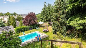 A backyard with a swimming pool, a trampoline, and a wooden fence. - Ruhige Gartenwohnung in Dresden (Dresden)