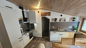 A modern kitchen with white cabinetry, a black stove, and a wooden dining table with a menu. - Beautiful vacation apartment on the edge of the forest with three bedrooms. (Bad König)