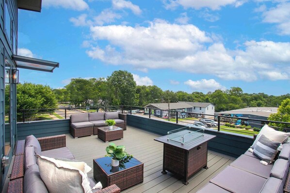Una terraza en la azotea con mobiliario exterior, una mesa con superficie de vidrio y vistas del entorno.