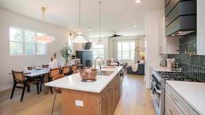 A modern kitchen with a central island, stainless steel appliances, and pendant lighting. - 4 BDR Stay for 12 w/Rooftop Patio Firepit! Near DT (Nashville)