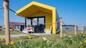 Een geel gebouw met een overdekte zitplaats en een touwbordes.