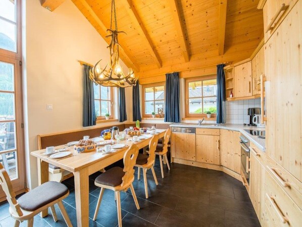 Un interior de madera con una mesa de comedor, sillas y una zona de cocina.