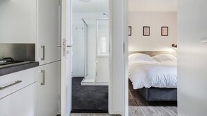 Une chambre d’hôtel moderne équipée d’un lit, d’une douche et d’une kitchenette.