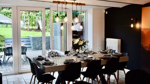 A modern dining area with a large table set for six, surrounded by chairs. - Holiday Home in Manhay near Ski Area (Manhay)