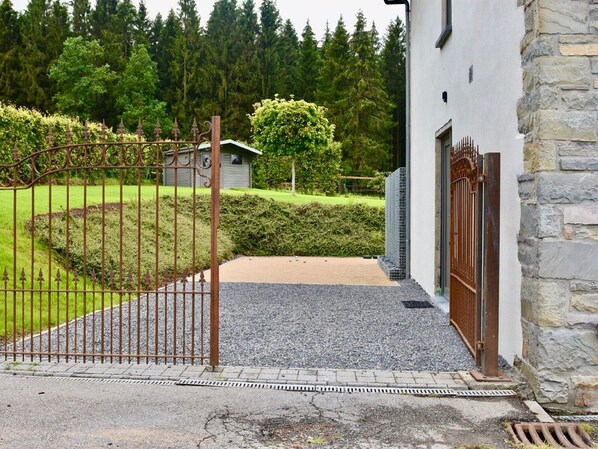 A gated entrance to a building with a gravel path leading to a door.