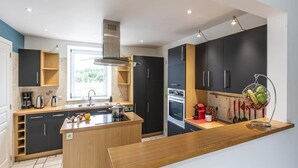 A modern kitchen with a central island, built-in appliances, and a window providing natural light. - Holiday Home in Manhay near Ski Area (Manhay)