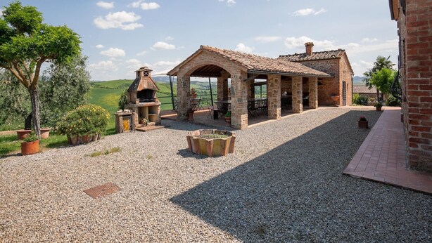 A rustic outdoor area with a stone barbecue, seating, and a view of the countryside. - Peccioli Family Retreat w/ Fun (Peccioli)