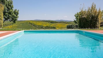 Ein rechteckiger Swimmingpool mit klarem, blauem Wasser, umgeben von einer Ziegelterrasse.