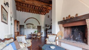 A traditional living room with a fireplace, wooden furniture, and a dining area. - Peccioli Family Retreat w/ Fun (Peccioli)