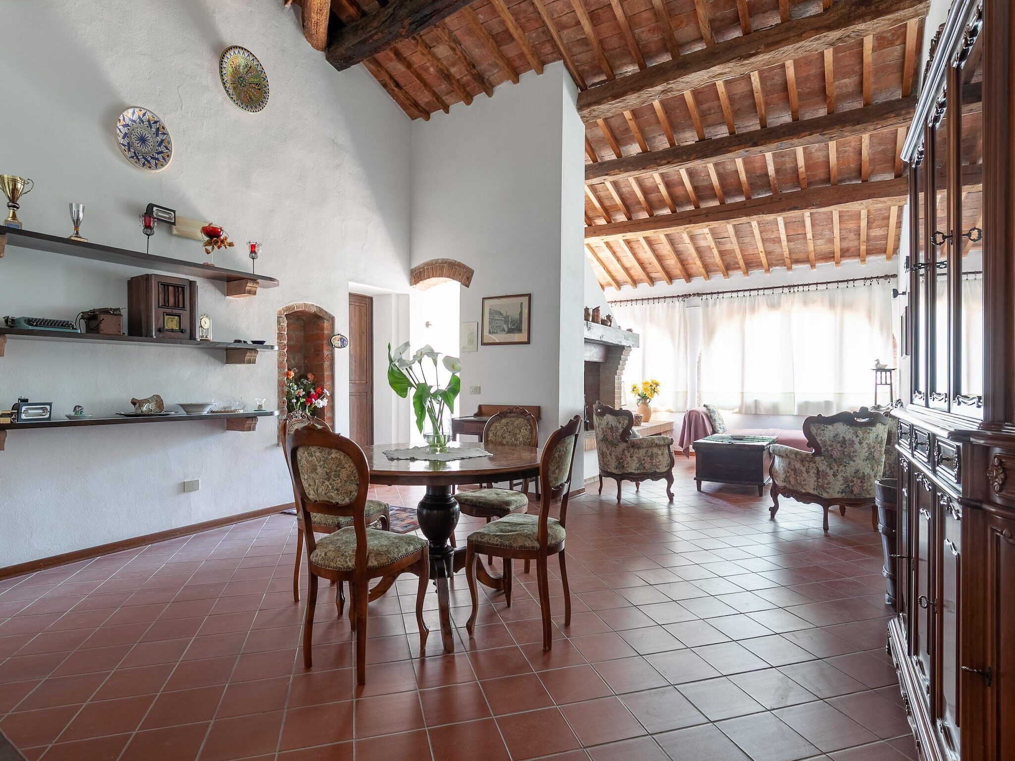 Un vaste espace dédié à la salle à manger, doté d’un haut plafond et de poutres apparentes, et agrémenté de meubles traditionnels et d’objets décoratifs.