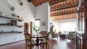 A spacious dining area with a high ceiling and exposed wooden beams, surrounded by traditional furniture and decorative items. - Peccioli Family Retreat w/ Fun (Peccioli)