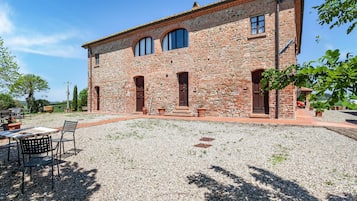 A stone building with a gravel courtyard, outdoor seating, and a view of the countryside.