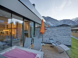 Zona relax esterna moderna con parete in pietra e vista sulle montagne.