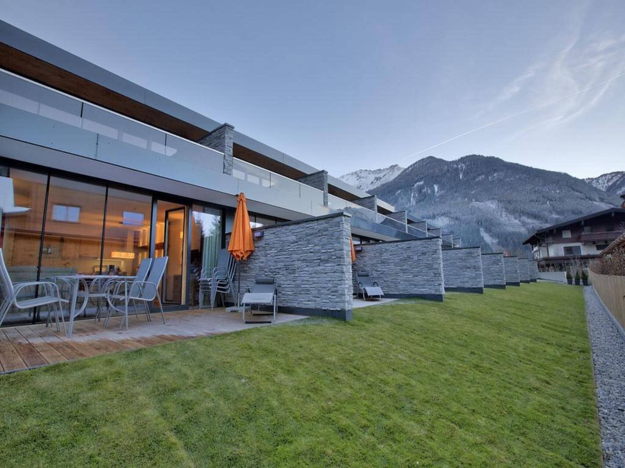 A modern building with a glass facade, outdoor seating, and a mountain backdrop.