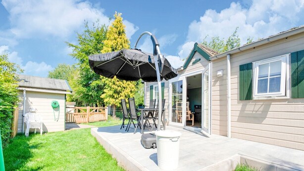 A patio area with a table and chairs, a covered seating area, and a small shed. - Chalet in Stegeren near Hiking Trails (Stegeren)