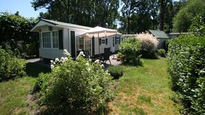 A mobile home with a patio area, surrounded by greenery and trees. - Chalet in Stegeren near Hiking Trails (Stegeren)