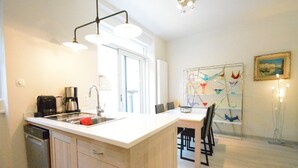 Een moderne keuken met een centraal eiland, inbouwmeubels en een eetgedeelte met een glazen scheiding.