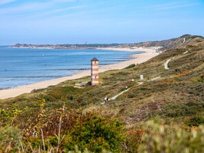 A coastal landscape with a lighthouse, beach, and walking paths. - Holiday Home in Koudekerke near the Beach (Koudekerke)