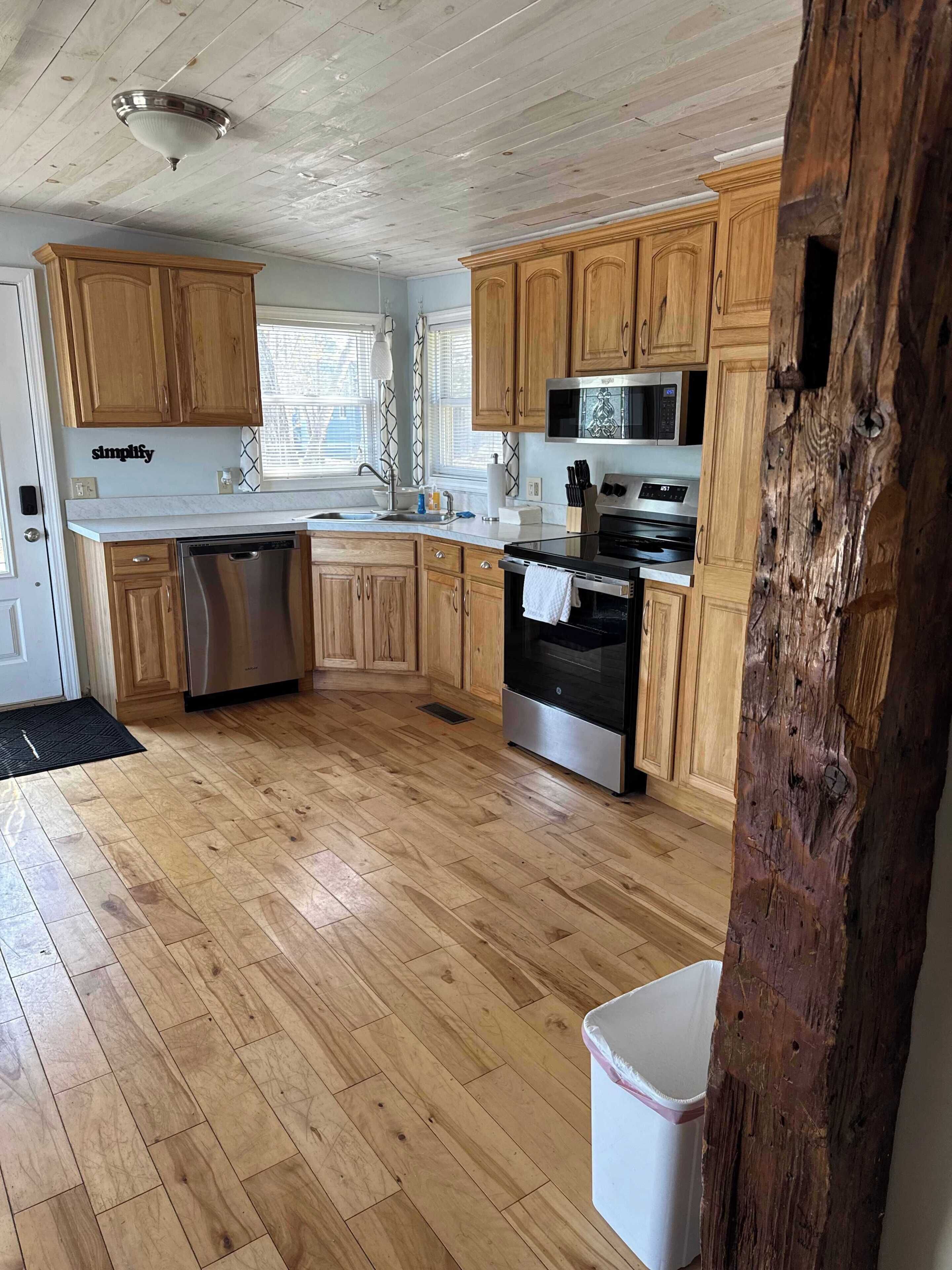 Une cuisine avec des armoires en bois, des appareils électroménagers en acier inoxydable et un plancher en bois.