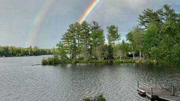 Une vue sur le lac avec un arc-en-ciel, un quai et des kayaks.