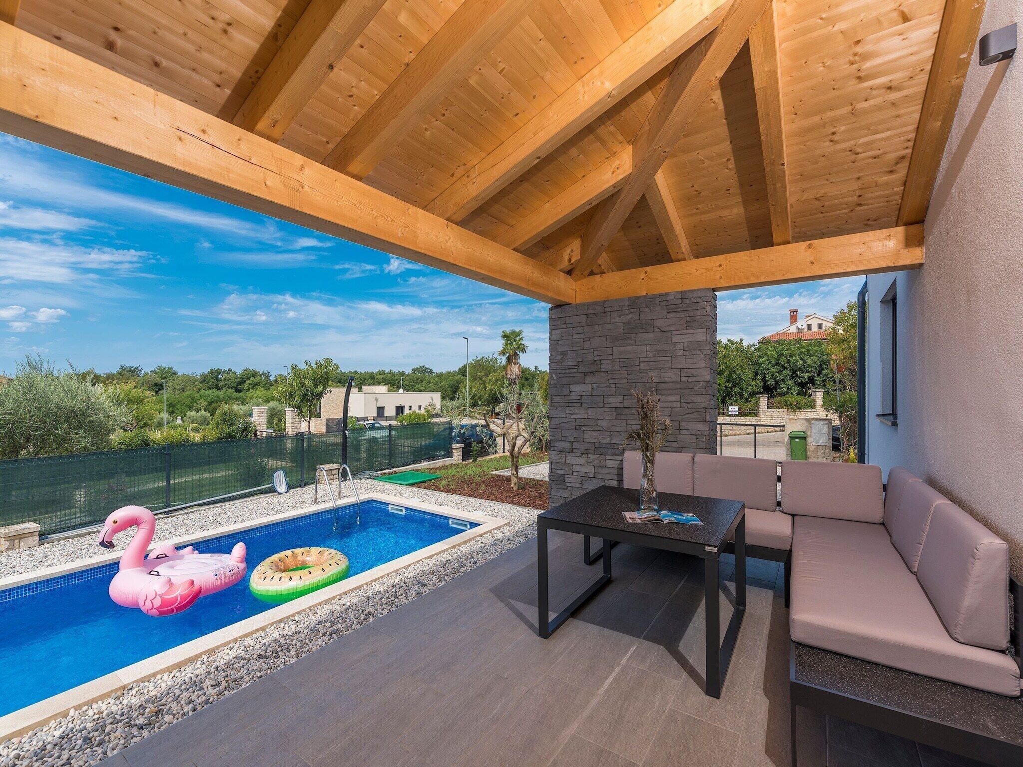 A covered outdoor area with a pool, seating, and a view of the surrounding landscape. - Villa in Novigrad with Private Pool and Beach (Novigrad)