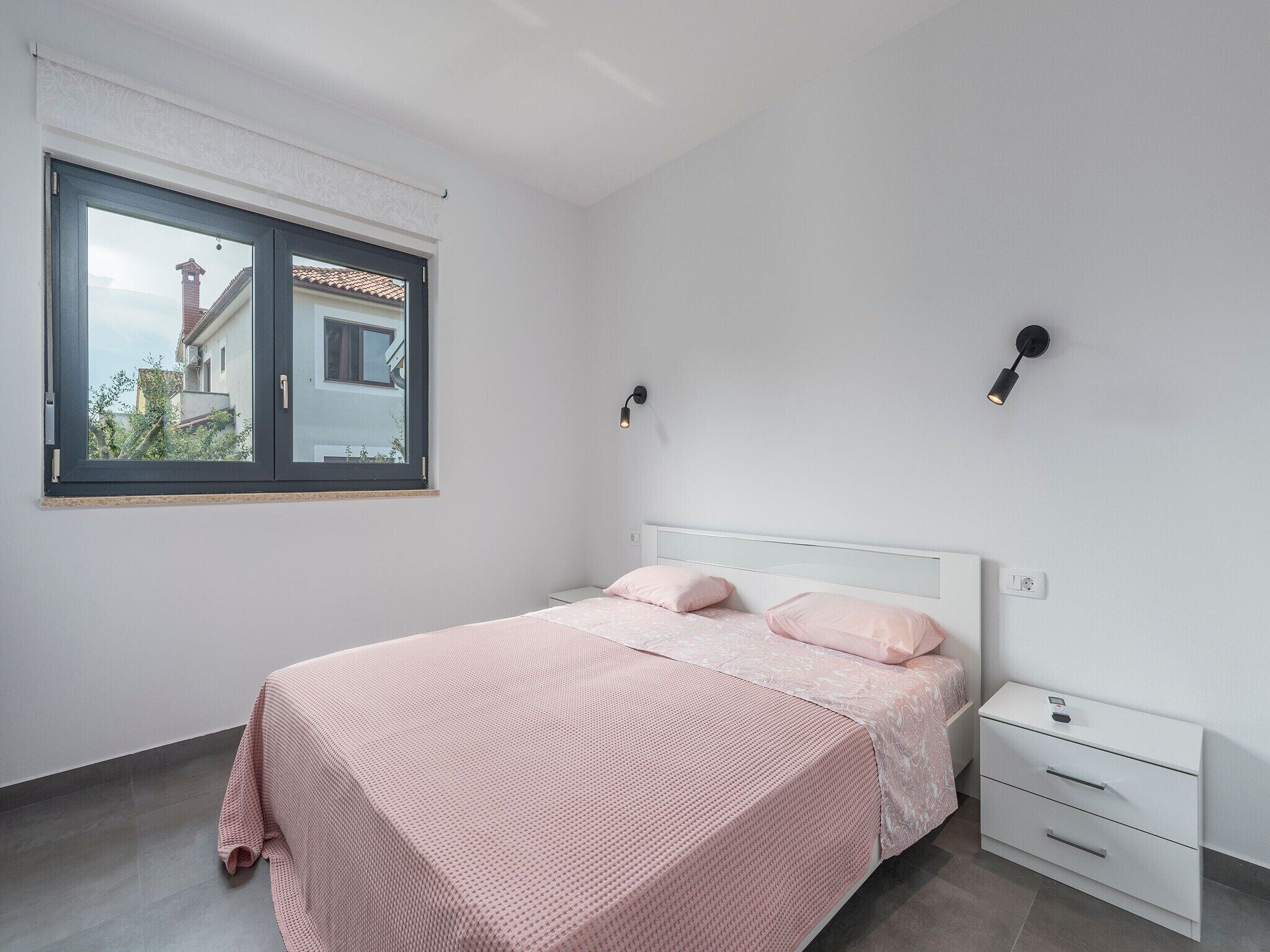 A bedroom with a bed, bedside tables, and a window.