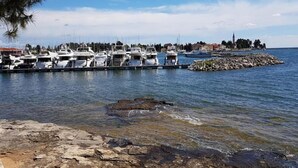 A marina with several boats docked, a rocky shoreline, and a distant town with buildings and a church. - Villa in Novigrad with Private Pool and Beach (Novigrad)