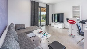 A modern living room with a sofa, a coffee table, a TV, and a bar area with stools. - Villa in Novigrad with Private Pool and Beach (Novigrad)