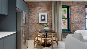 A modern kitchen with a brick wall, a dining area with a round table and chairs, and a large window with curtains. - Mercer-2BDR 2BA Old Montreal- Free parking (Montréal)