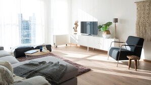 Una sala de estar moderna con un sofá, una mesa de centro y un televisor sobre un mueble blanco.