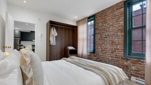 Ein Schlafzimmer mit einem großen Bett, einem Holzschrank und einer Ziegelwand.