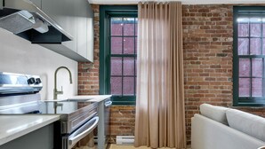 Eine Küche mit Backsteinwand, einem Fenster mit Vorhang und einer Couch.
