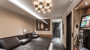 A modern hotel lobby with a gray sectional sofa, a wooden cabinet with a coffee machine, and a large mirror on the wall. - Luxury Chalet Gaschurn near Ski Lift (Gaschurn)