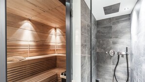 A modern bathroom with a wooden sauna bench and a separate shower area with grey tiles. - Luxury Chalet Gaschurn near Ski Lift (Gaschurn)