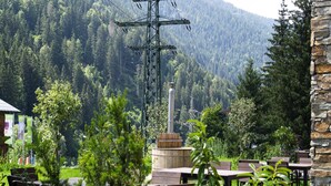 An outdoor seating area with tables and chairs, surrounded by greenery and a mountainous backdrop. - Luxury Chalet Gaschurn near Ski Lift (Gaschurn)