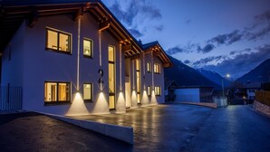 A modern two-story house with a well-lit entrance and a driveway leading to a garage. - Luxury Chalet Gaschurn near Ski Lift (Gaschurn)