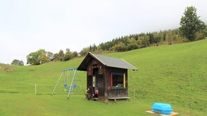 A small wooden cabin with a swing set in a grassy field. - Apartment in Fresach near Ski Slopes (Fresach)