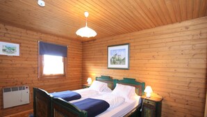 A wooden-paneled bedroom with a bed, two bedside lamps, a window, and a radiator. - Apartment in Fresach near Ski Slopes (Fresach)
