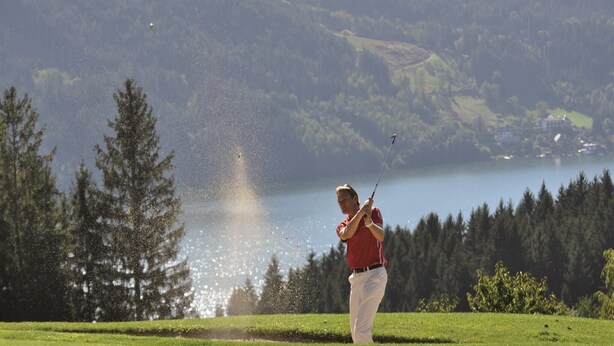 A golfer on a golf course with a lake and forest in the background. - Apartment in Fresach near Ski Slopes (Fresach)
