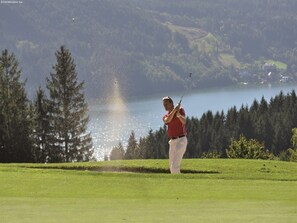 A golfer on a golf course with a lake and forest in the background. - Apartment in Fresach near Ski Slopes (Fresach)