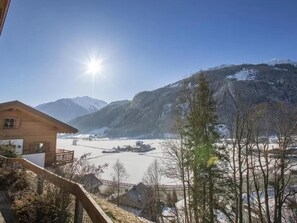 A wooden cabin with a view of a snowy landscape and mountains.