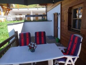 Un área de estar al aire libre con una mesa, sillas, un florero y una valla de madera.