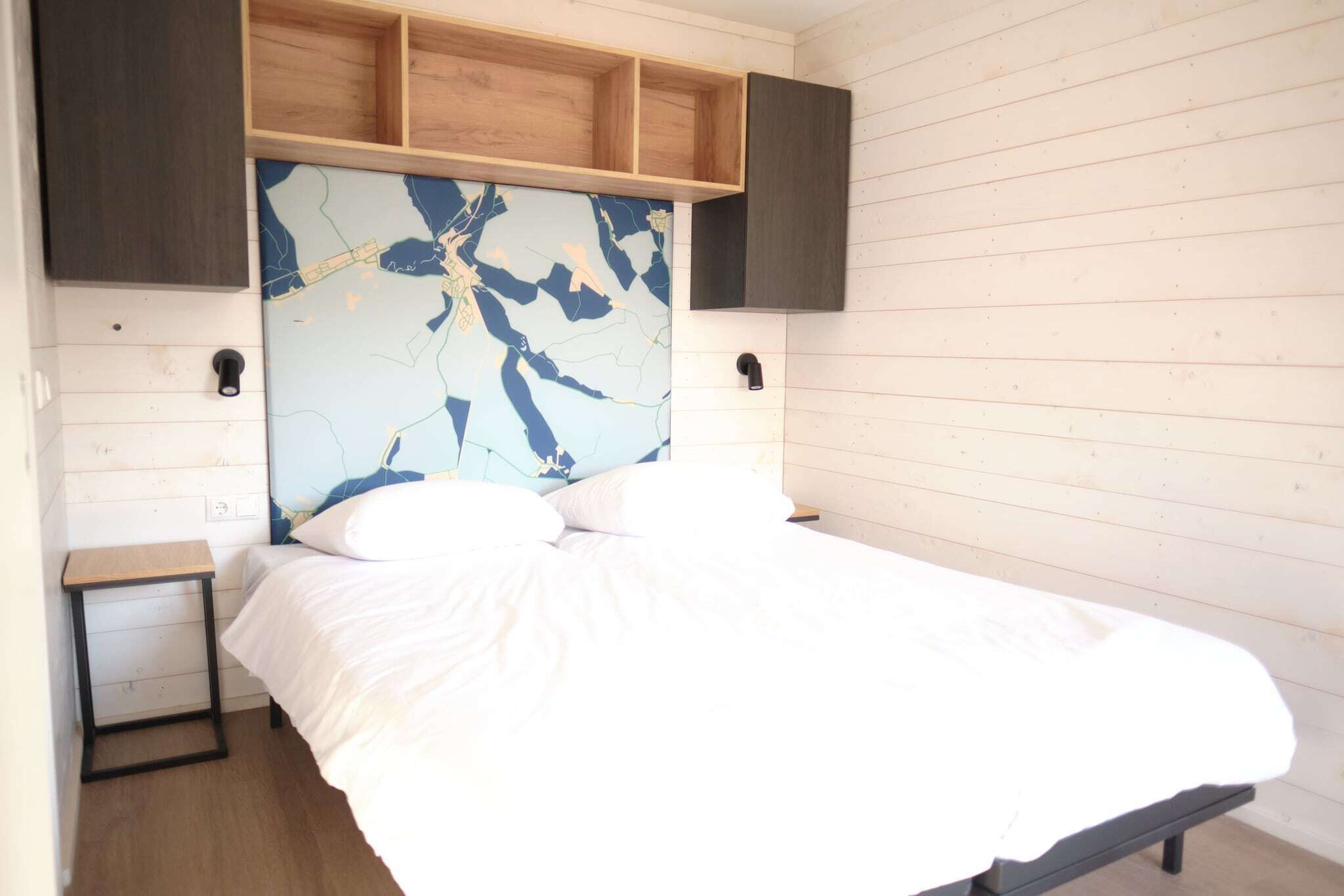 A bedroom with a bed, a wooden headboard, a nightstand, and a wall-mounted shelf.