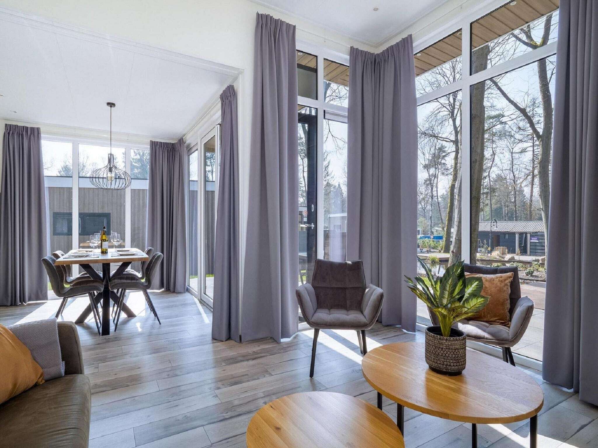Un salon moderne avec un coin repas, de grandes fenêtres et une vue sur l’extérieur.