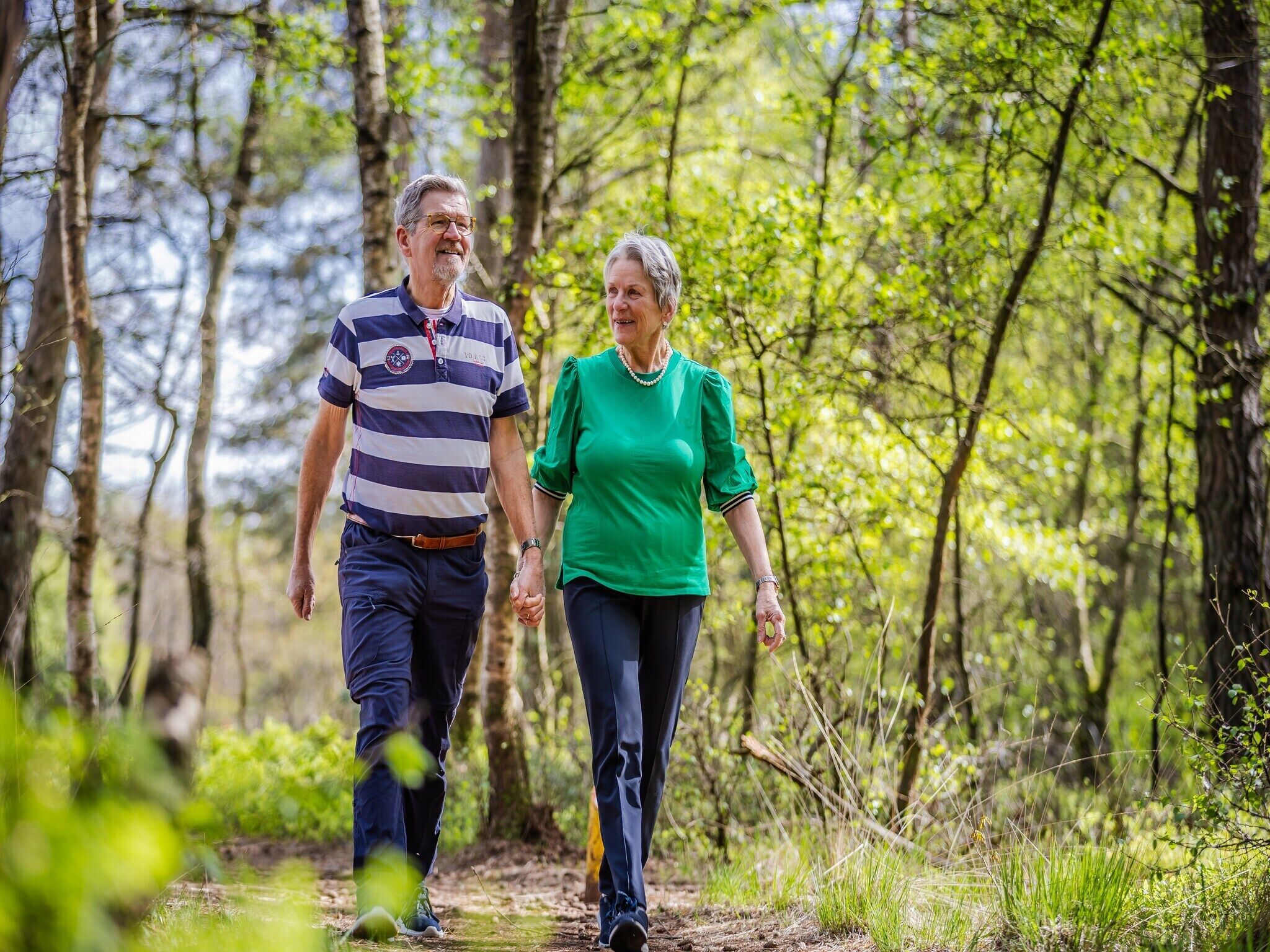 Dos personas caminando por un sendero en el bosque.