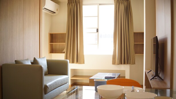 A modern living room with a sofa, a dining table with chairs, a television, and a window with curtains. - The Parkland Bangna Next MRT Station (Bangkok)